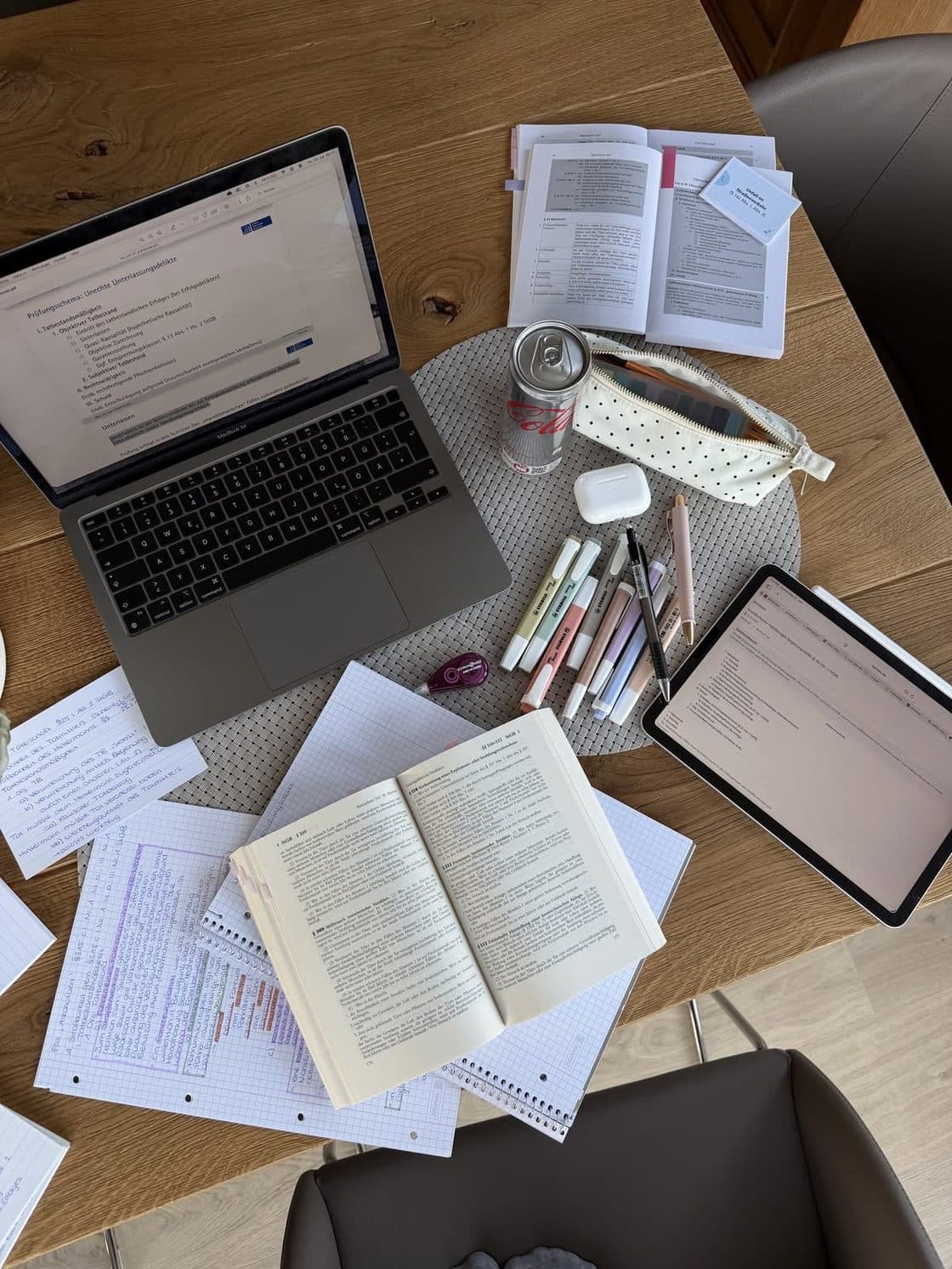 Escritorio de estudio con una laptop, libros, apuntes y marcadores